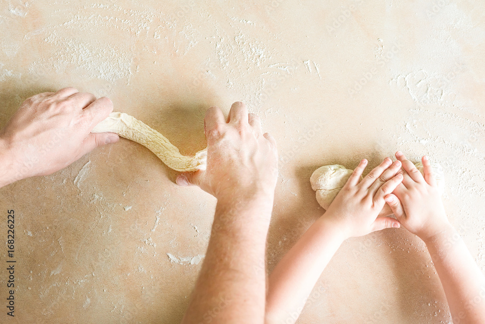 Fototapeta premium Children's and dad's hands makes raw dough
