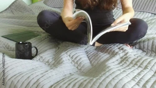 Yong woman with magazine in the bed in bedroom, slow motion video photo