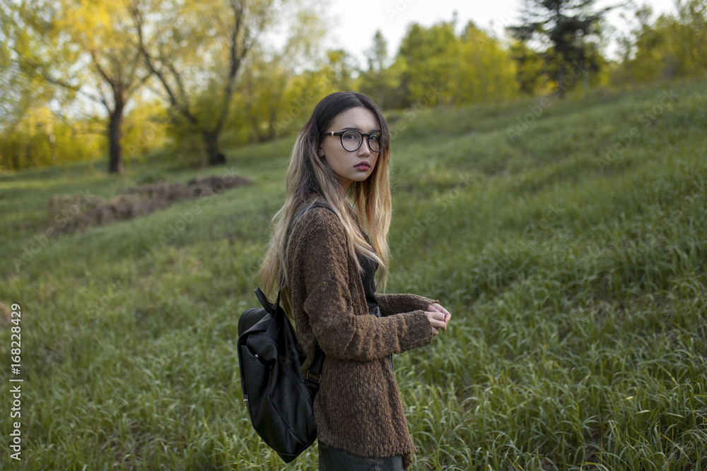 Asian teenage girl carrying backpack in field Asian teenage girl carrying backpack in field