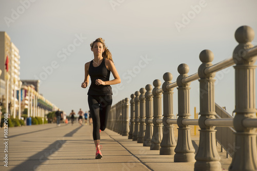 Caucasian teenage girl running on boardwalk photo