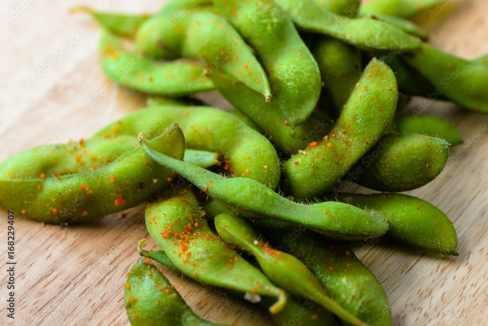 Edamame bean. Boiled immature soybeans in pods on a wooden cutting board with blurred background. Asian traditional food. Macro food photo for cafe, menu, restaurant, design, interior, web, sites. Edamame bean. Boiled immature soybeans in pods on a wooden cutting board with blurred background. Asian traditional food. Macro food photo for cafe, menu, restaurant, design, interior, web, sites.