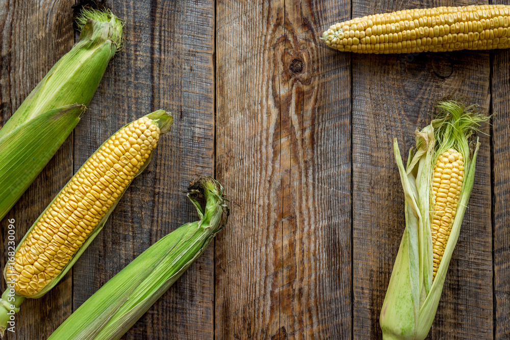 Vegetarian food. Corn cobs on rustic wooden background top view copyspace