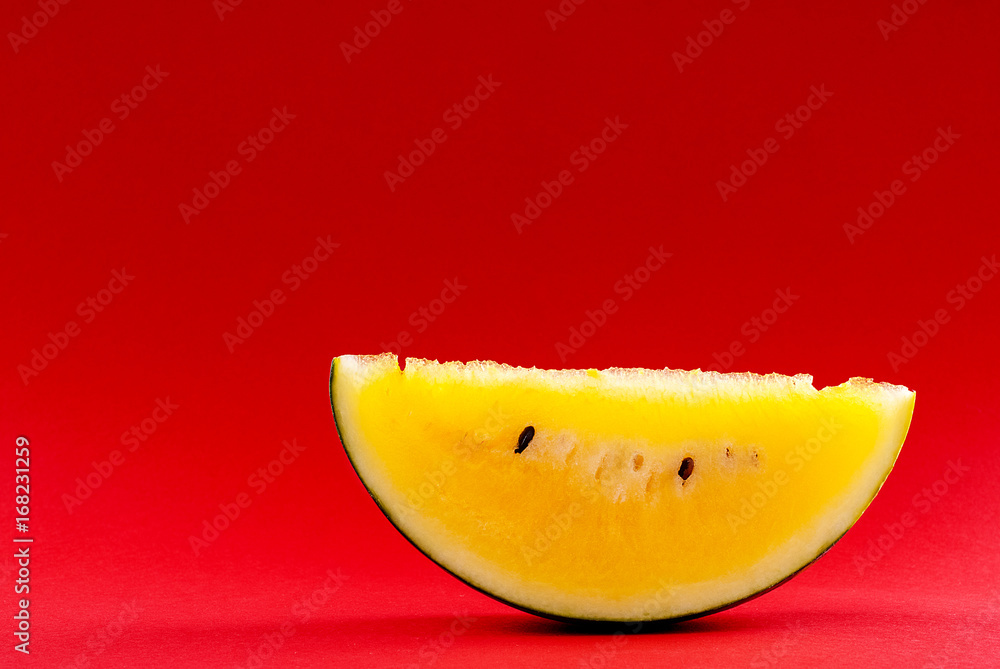 sliced watermelon with yellow flesh on a red background