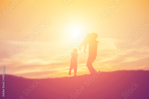 Silhouettes of father and little daughter walking at sunset