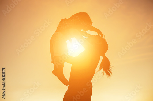 Mother encouraged her daughter out of the shadows at sunset.