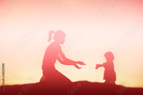 Mother encouraged her daughter out of the shadows at sunset.