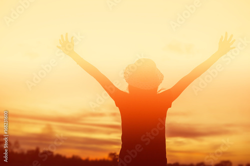 Silhouette of woman praying over beautiful sky background © chaunpis