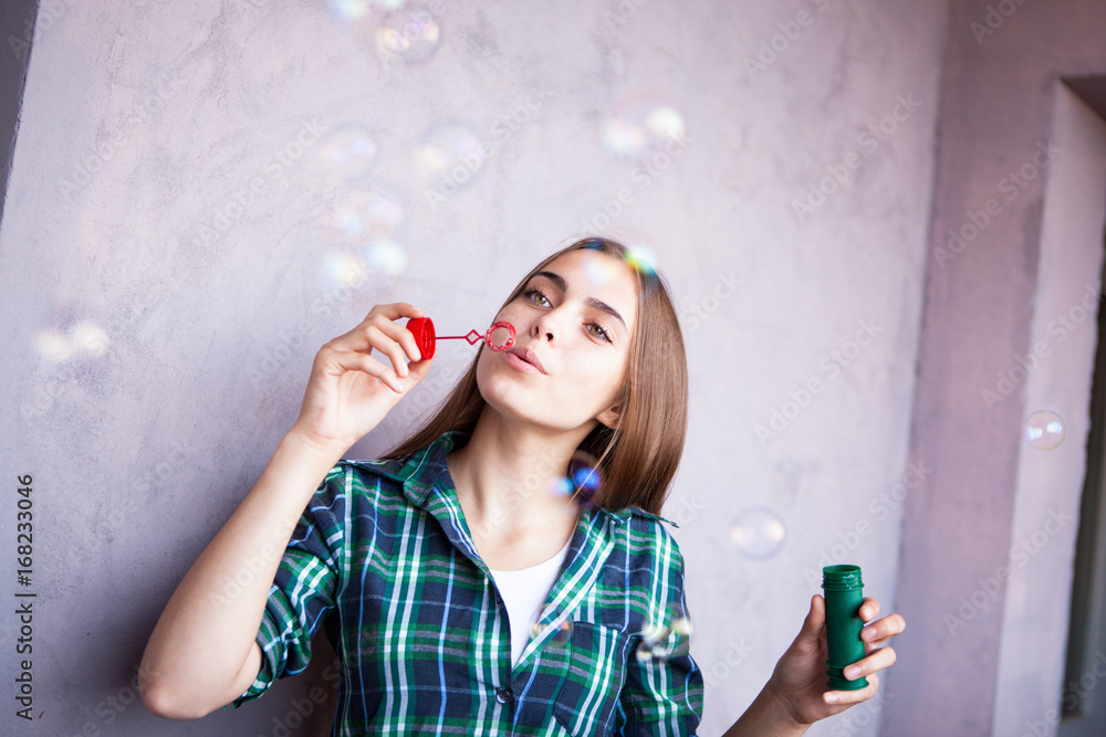 Beautiful girl with freckles blowing bubbles near pink wall Beautiful girl with freckles blowing bubbles near pink wall