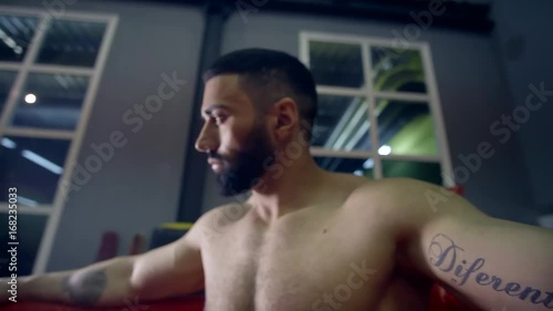 muscular heavyweight boxer resting in the corner of the ring leaning back on the ropes