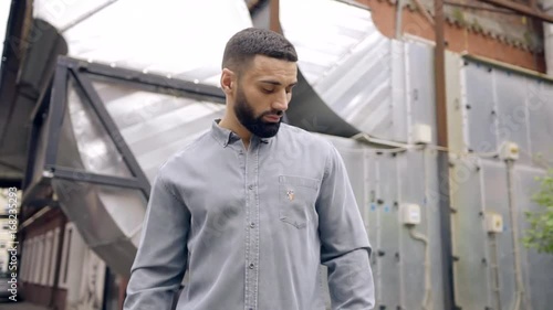 Wallpaper Mural a young man with dark hair and beard stands on the background of metal structures. grey clothes. the camera zooms upwards Torontodigital.ca