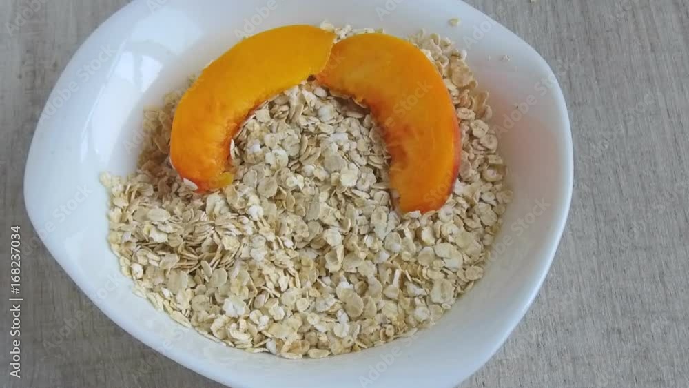 Oat flakes in plate fall peach slices slow motion footage Oat flakes in plate fall peach slices slow motion footage