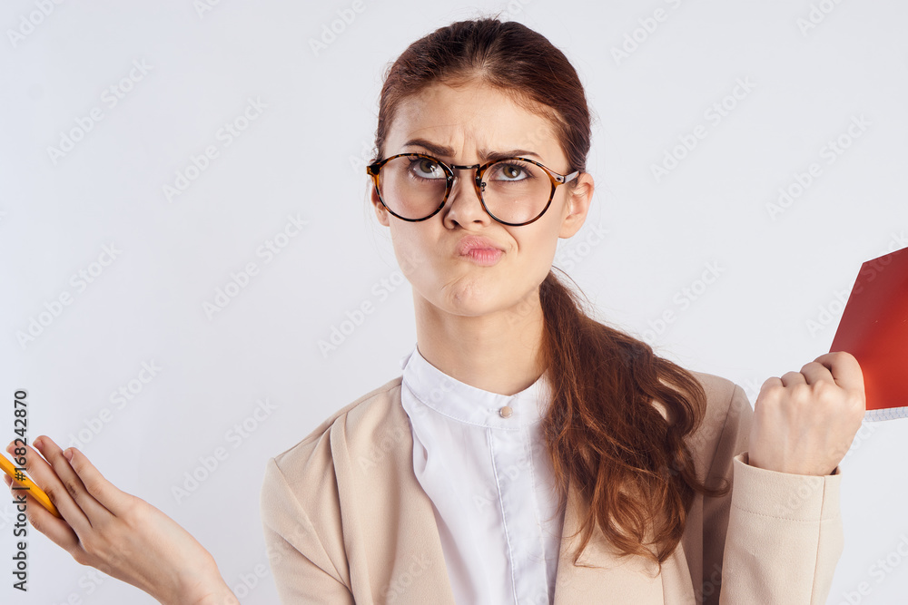 Young beautiful woman on a light background with glasses holds a notebook, portrait, emotions, teacher Young beautiful woman on a light background with glasses holds a notebook, portrait, emotions, teacher