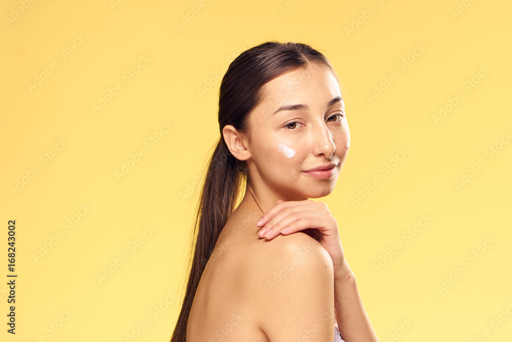 Young beautiful woman on a yellow background, cosmetic cream, beauty, skin care Young beautiful woman on a yellow background, cosmetic cream, beauty, skin care