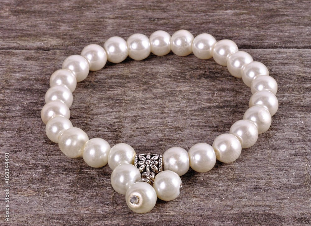 White bracelet with artificial beads on a wooden background White bracelet with artificial beads on a wooden background