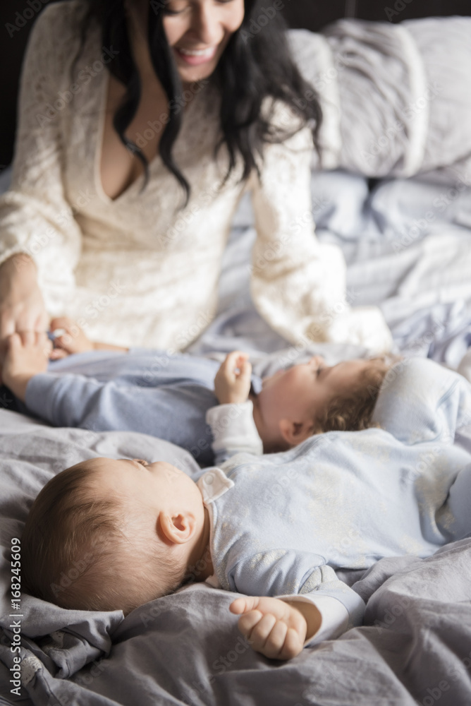 Mother sitting on bed playing with sons Mother sitting on bed playing with sons