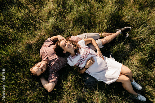 High angle view of first time parents resting on lawn and having fun. Top view of a smiling couple expecting their first child relaxing in the nature.