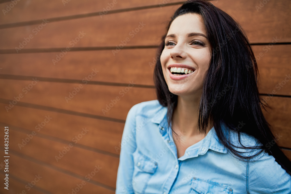 Beautiful smiling girl on the background of a wooden wall Beautiful smiling girl on the background of a wooden wall