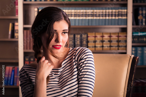 Photography Young caucasian woman dressed like Jackie Kennedy poses in a library