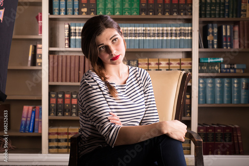 Young caucasian woman dressed like Jackie Kennedy poses in a library photo
