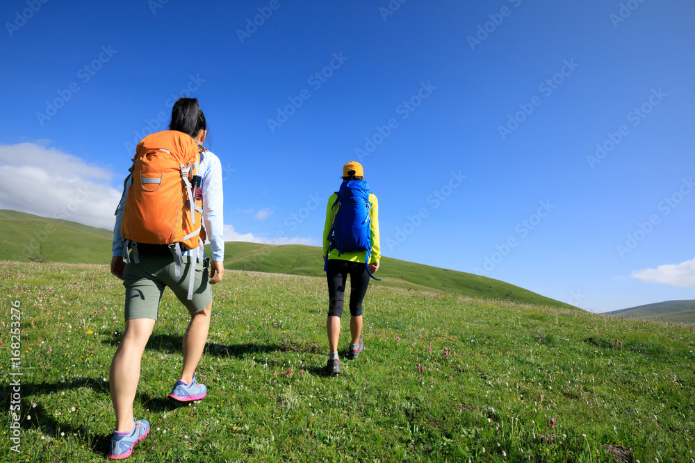 two women friends hiking in grassland mountains top two women friends hiking in grassland mountains top