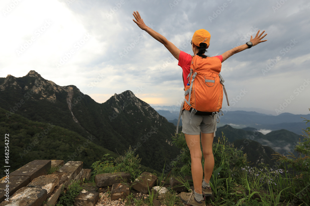 successful woman hiker open arms on the top of mountain