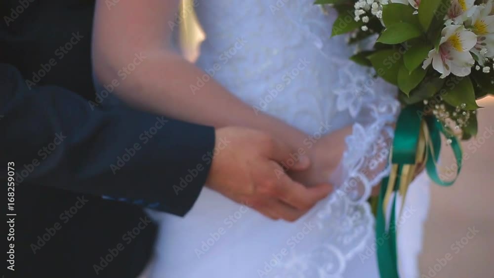 Beautiful bride and groom standing on a balcony overlooking the sea Beautiful bride and groom standing on a balcony overlooking the sea