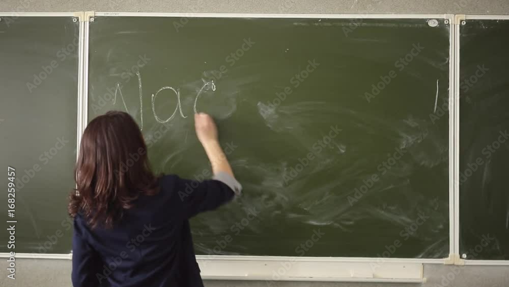 A young girl writes chalk on a white board with the word A young girl writes chalk on a white board with the word