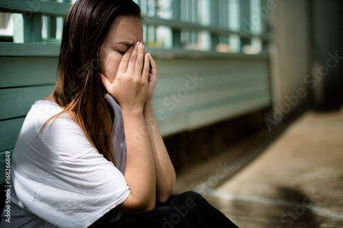 Depressed woman sitting with her hands covering her face overwhelmed with emotion photo