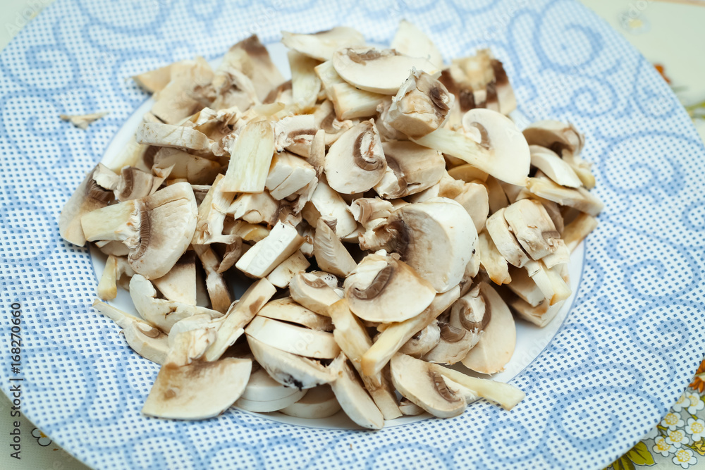 Detail of chopped champignons on a plate on kitchen table.