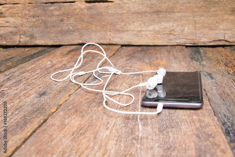 white earphone on mobile phone with table old wooden vintage background and copy space select focus with shallow depth of field white earphone on mobile phone with table old wooden vintage background and copy space select focus with shallow depth of field