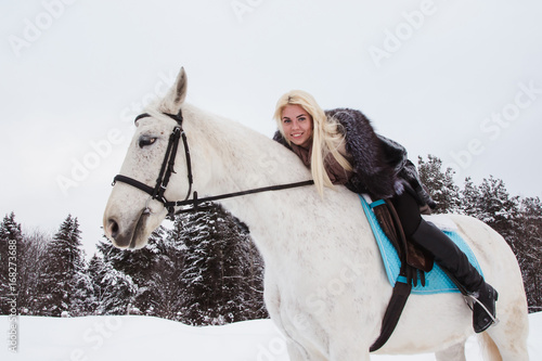 Nice girl and white horse outdoor in a winter