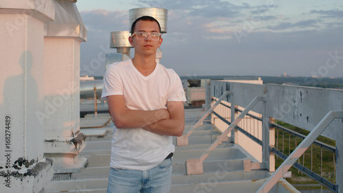 Portrait of a man on the roof of a tall building at sunset