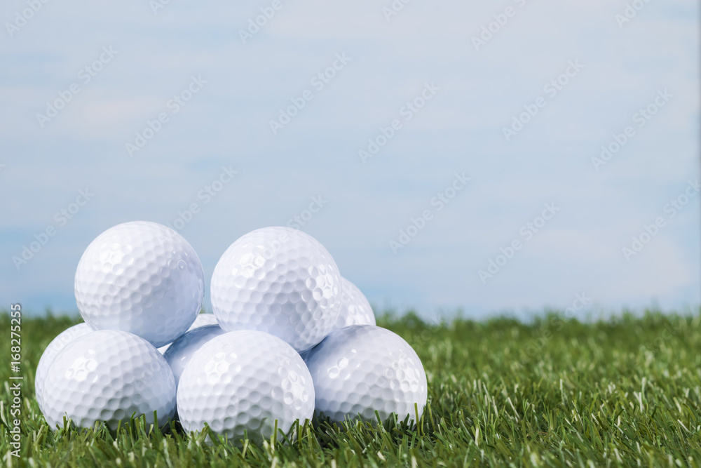 Many golf balls lie on the green grass against the blue sky Many golf balls lie on the green grass against the blue sky