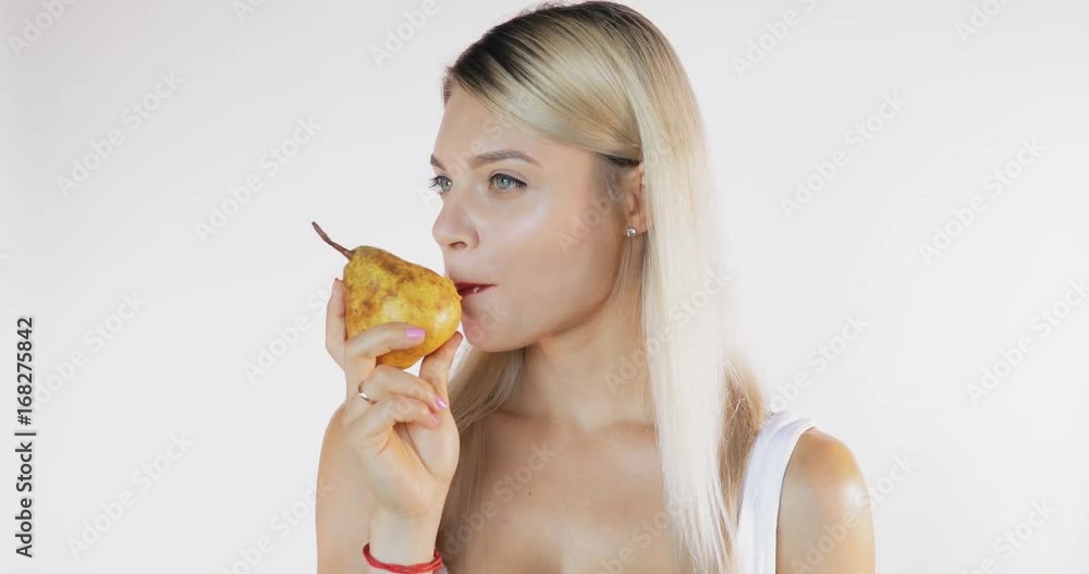 Attractive woman in shirt eating a big juicy pear isolated on white background with sound Attractive woman in shirt eating a big juicy pear isolated on white background with sound