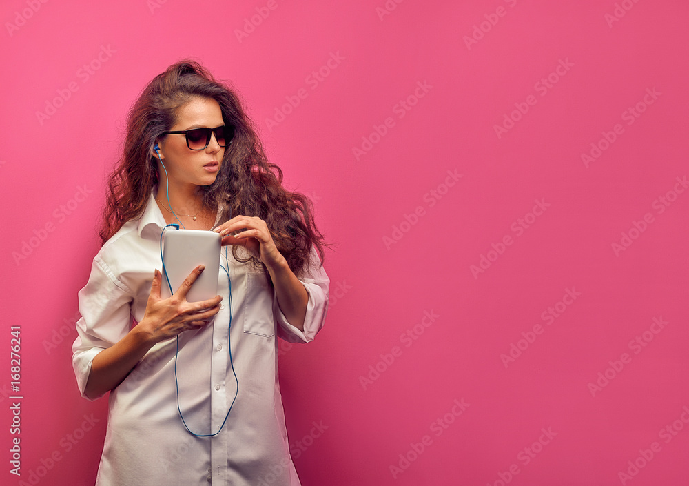 Cute young caucasian brunette woman in a white shirt  in glasses with headphones