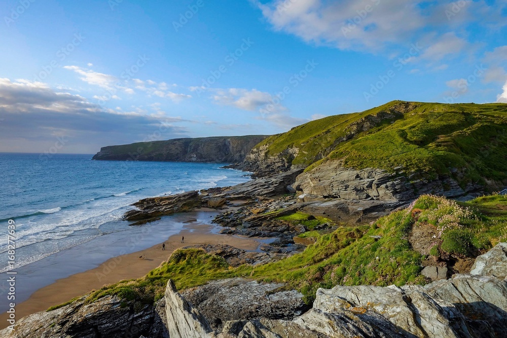 Rocky coastline with green grass on the cliff top facing the open sea on a bright sunny day
