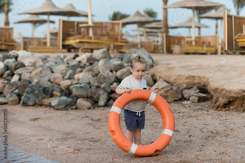Boy small kid holding orange ring saver at coast