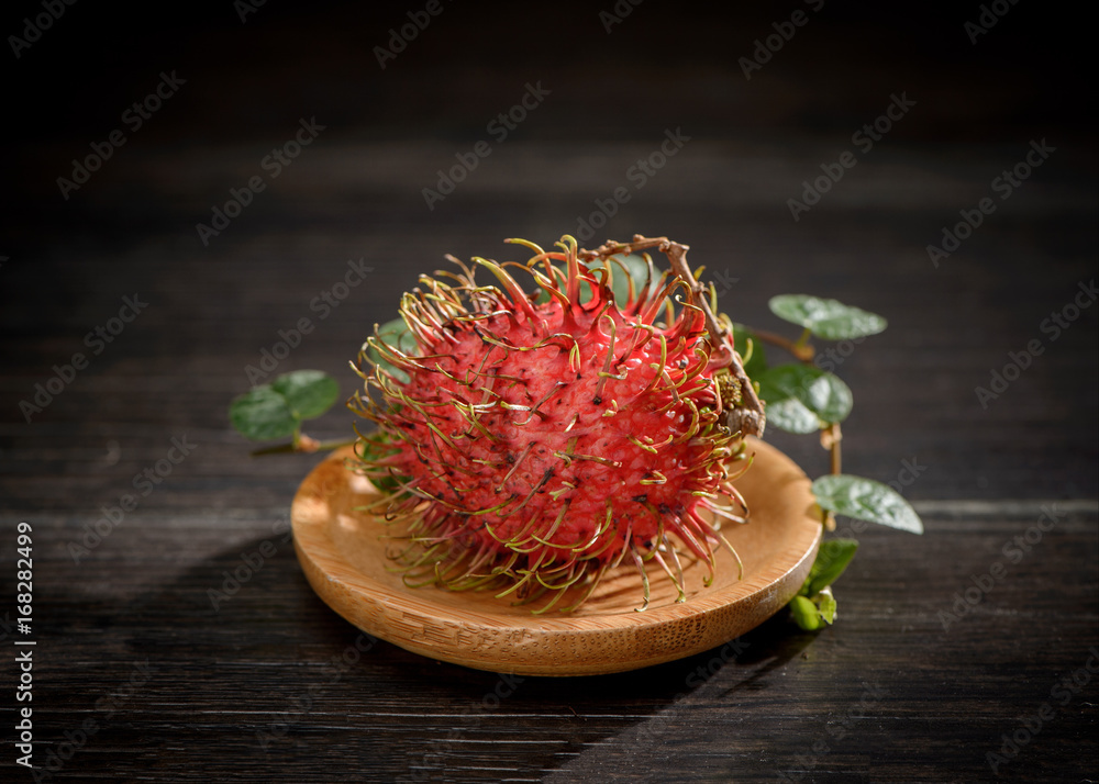 rambutan with vanilla on wooden plate isolated on the black background. rambutan with vanilla on wooden plate isolated on the black background.