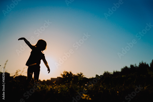 silhouette of little girl play at sunset