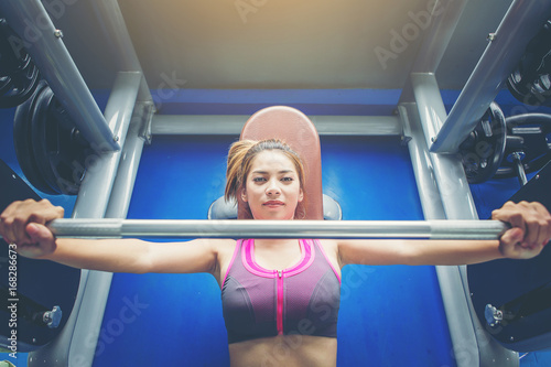 top view Sporty girl doing weight bar exercises at public gym.
