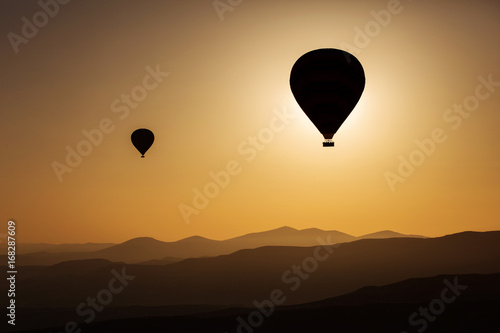 Silhouette of balloons with sunrise in background, aerial view