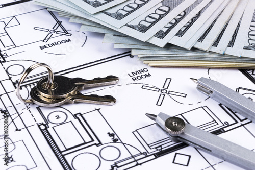 Stack of money with key lying on construction drawing of house, blueprint house plan concept, money for new real estate. blueprint and drawing instruments on the worktable.