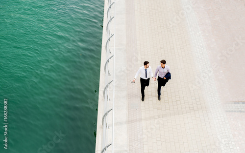 Photography Top view of two stylish businessmen walking near the river.