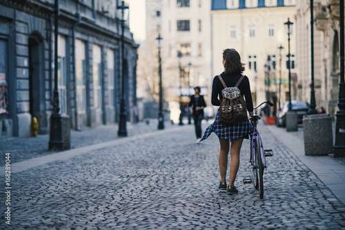 Hipster girl with a bike walking on the street