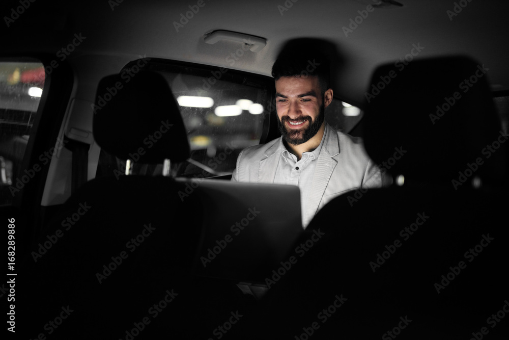 Elegant modern businessman is working on the back seat of his car. Elegant modern businessman is working on the back seat of his car.