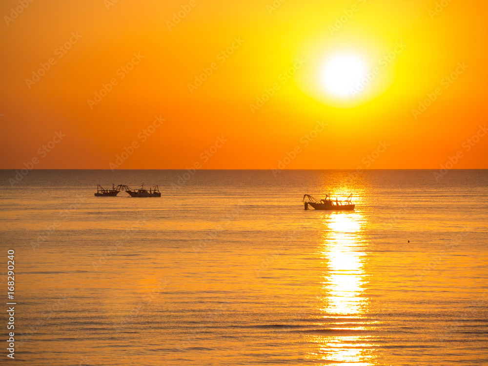 Fishing boats pull their nets at the sunrise. Adriatic cost. Emilia Romagna. Italy