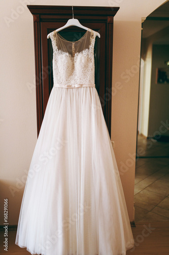 A beautiful wedding dress hanging in a room