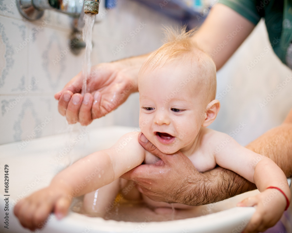 Happy laughing baby taking a bath. Little child in a bathtub. Smiling kid in bathroom. Infant washing and bathing. Hygiene and care for young children. Happy laughing baby taking a bath. Little child in a bathtub. Smiling kid in bathroom. Infant washing and bathing. Hygiene and care for young children.