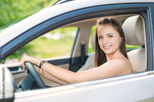 Beautiful young woman sitting in the interior of a new car with a smile. © REDPIXEL