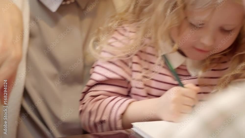 Closeup of little boy building jenga tower with grandmother while his cute sister drawing with pencil on table in the cafe Closeup of little boy building jenga tower with grandmother while his cute sister drawing with pencil on table in the cafe